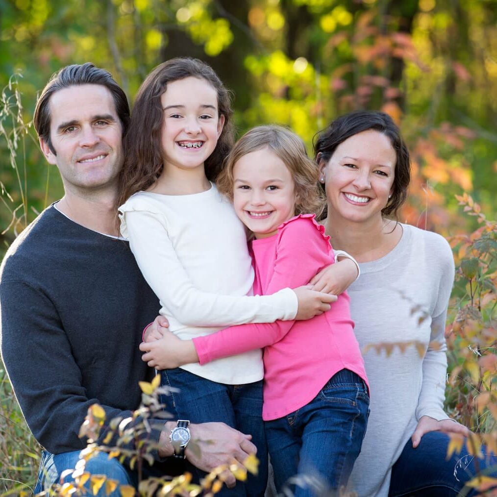 A family posing for a picture in the woods.